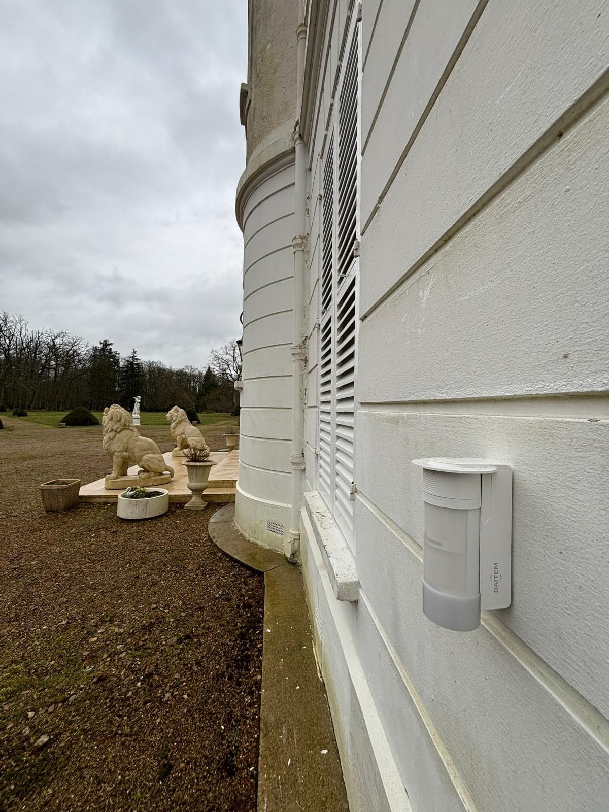 Détecteur extérieur fixé sur la façade d'un château, parc en arrière-plan