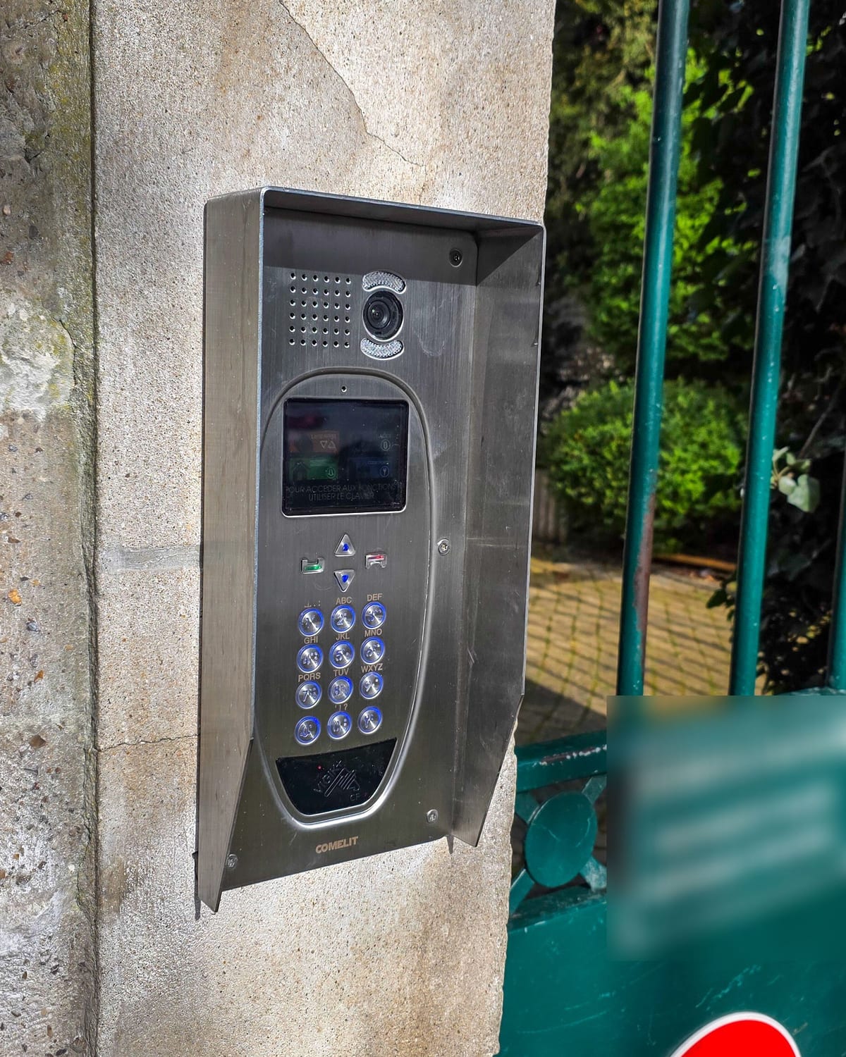 Platine d'interphonie sous casquette anti-intempéries à l'entrée piétonne d'une résidence