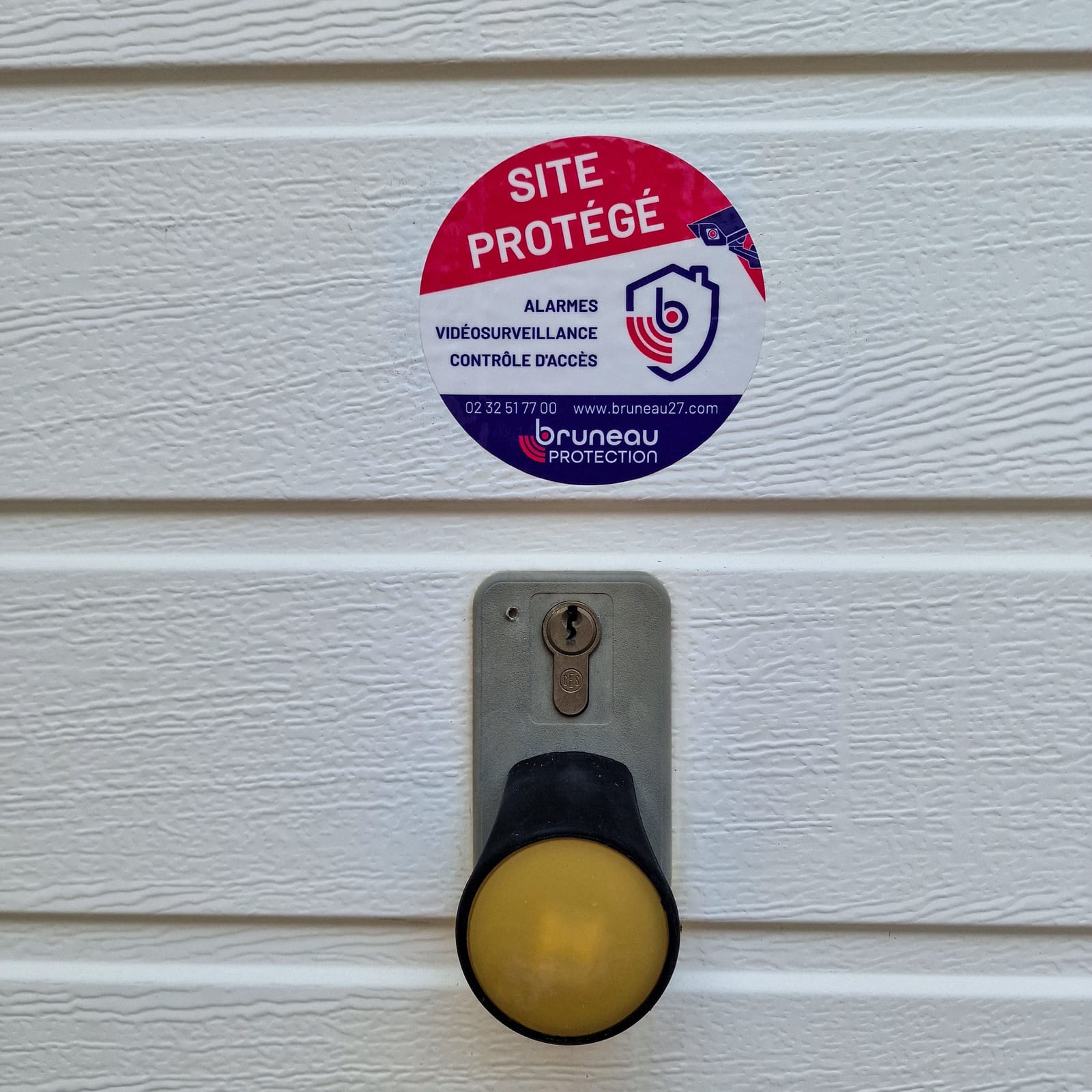 Macaron « Site protégé » sur la porte de garage d'une maison équipée d'une alarme